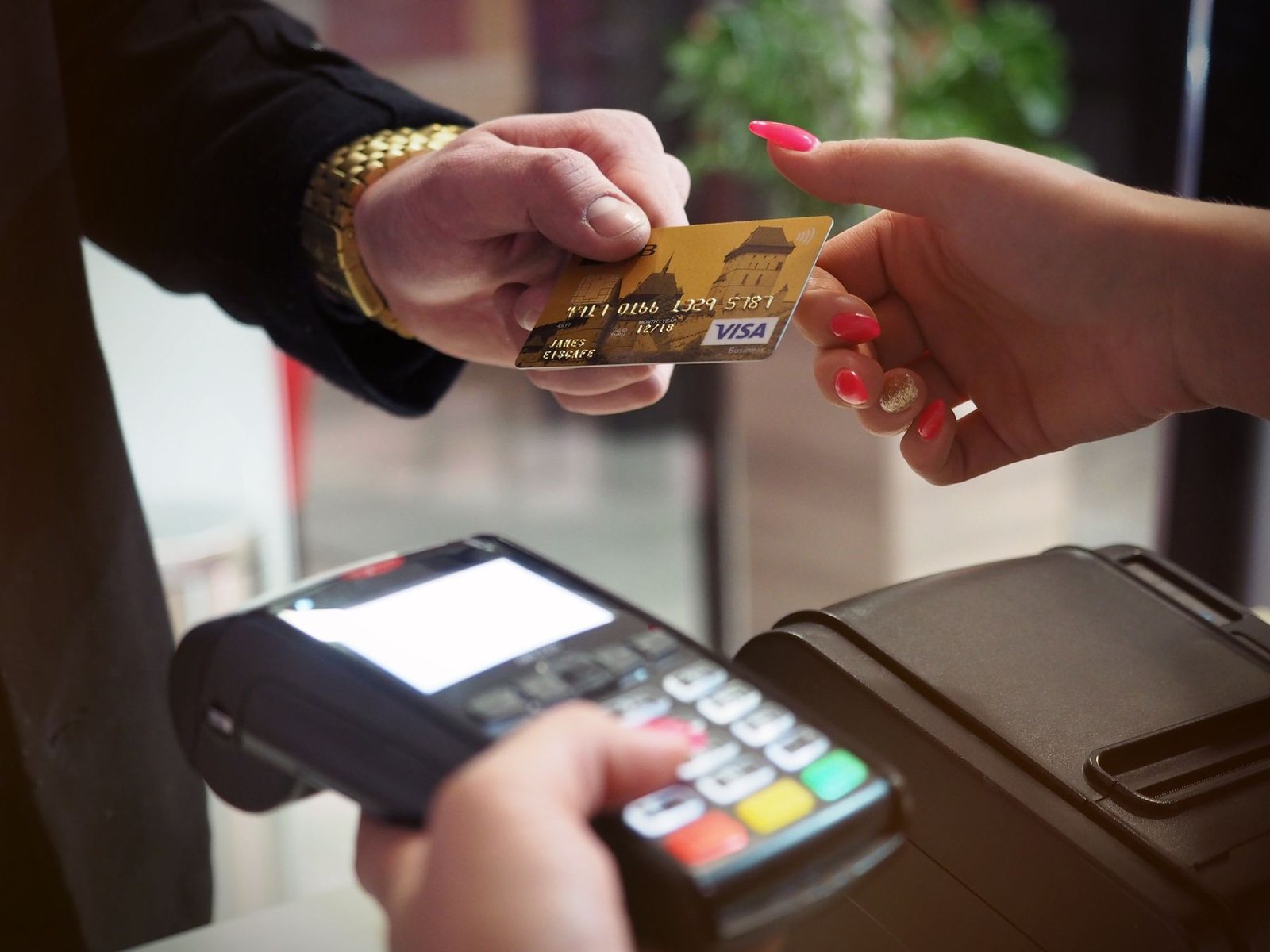 A Visa check card handed over a payment terminal at a store counter