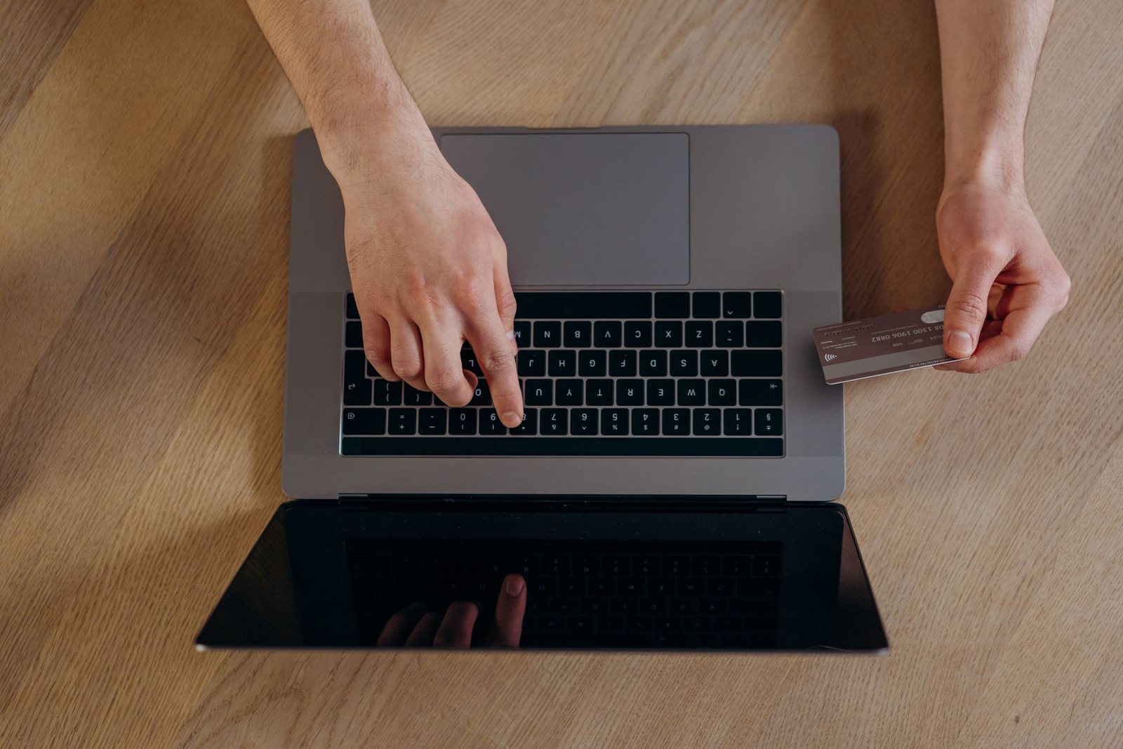Hands at a laptop keyboard holding a bank card